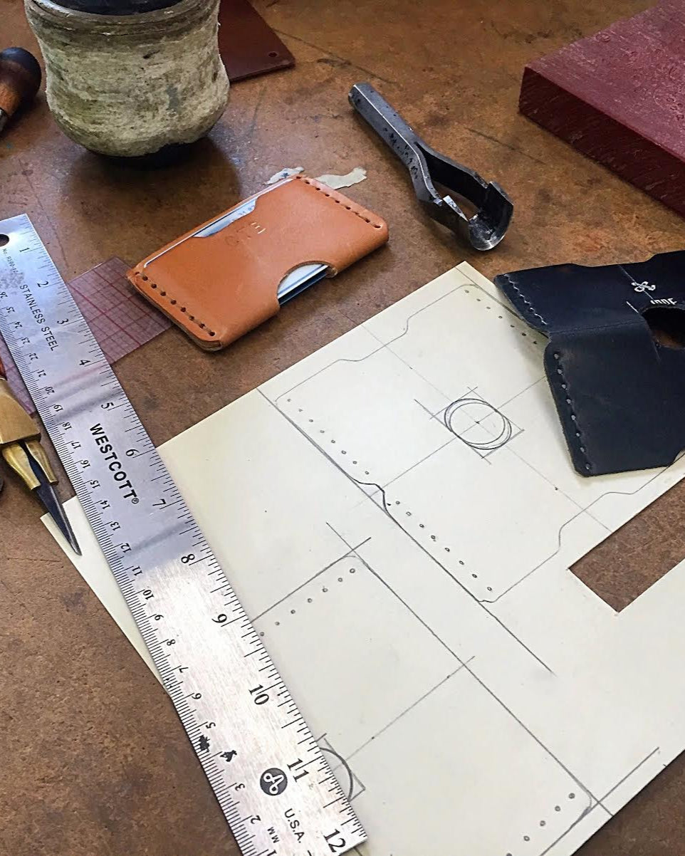 Workbench with leather crafting tools and materials including a ruler, leather pieces, and a pattern sheet.