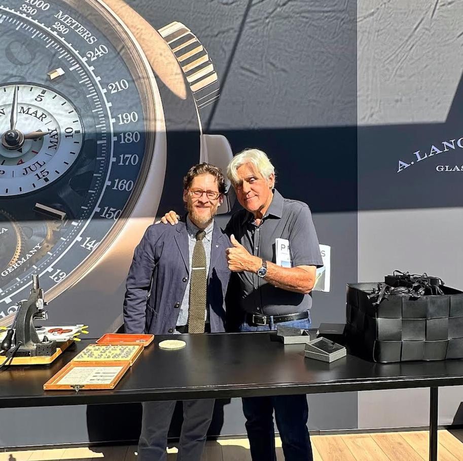 Two men standing in front of a display with a large watch and A. Lange & Söhne branding.