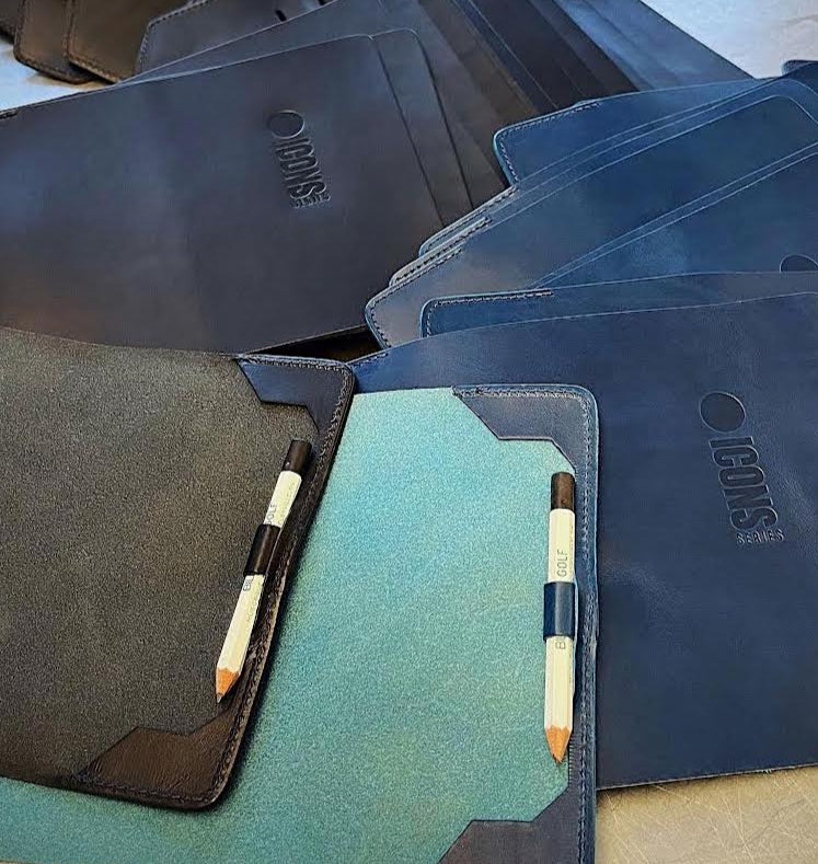 Collection of black and blue leather notebooks with pencil holders on a wooden surface.
