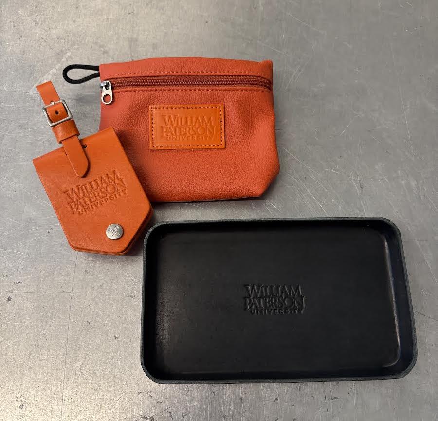 Orange leather pouch and tag with a black tray on a gray surface, featuring 'William Patrick' branding.