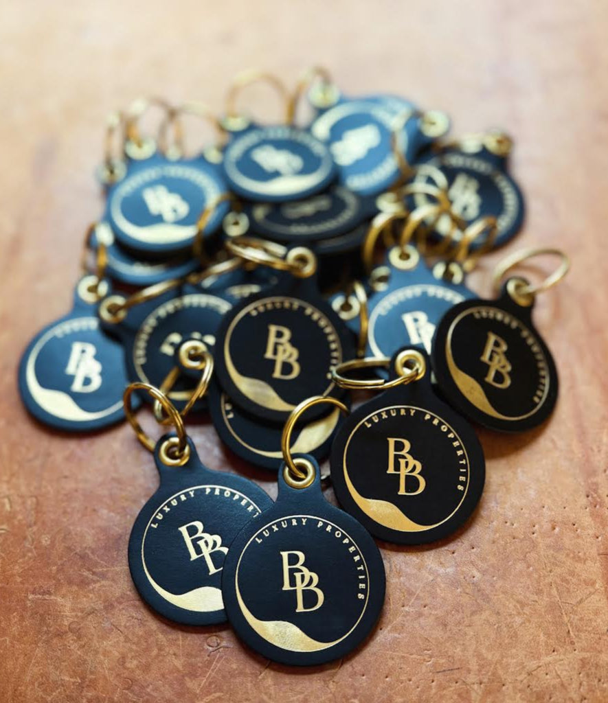 Collection of black and gold dog tags with a logo on a wooden surface