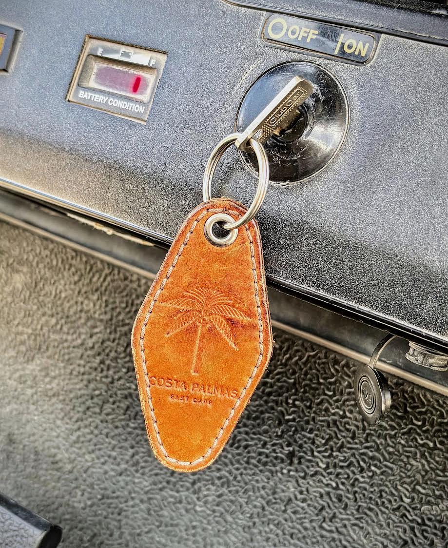Leather keychain with palm tree design attached to a suitcase lock.