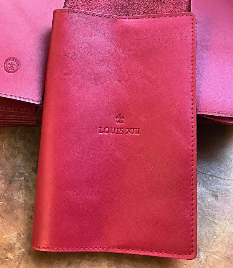 Pink leather wallet with 'Louis XIII' branding on a wooden surface