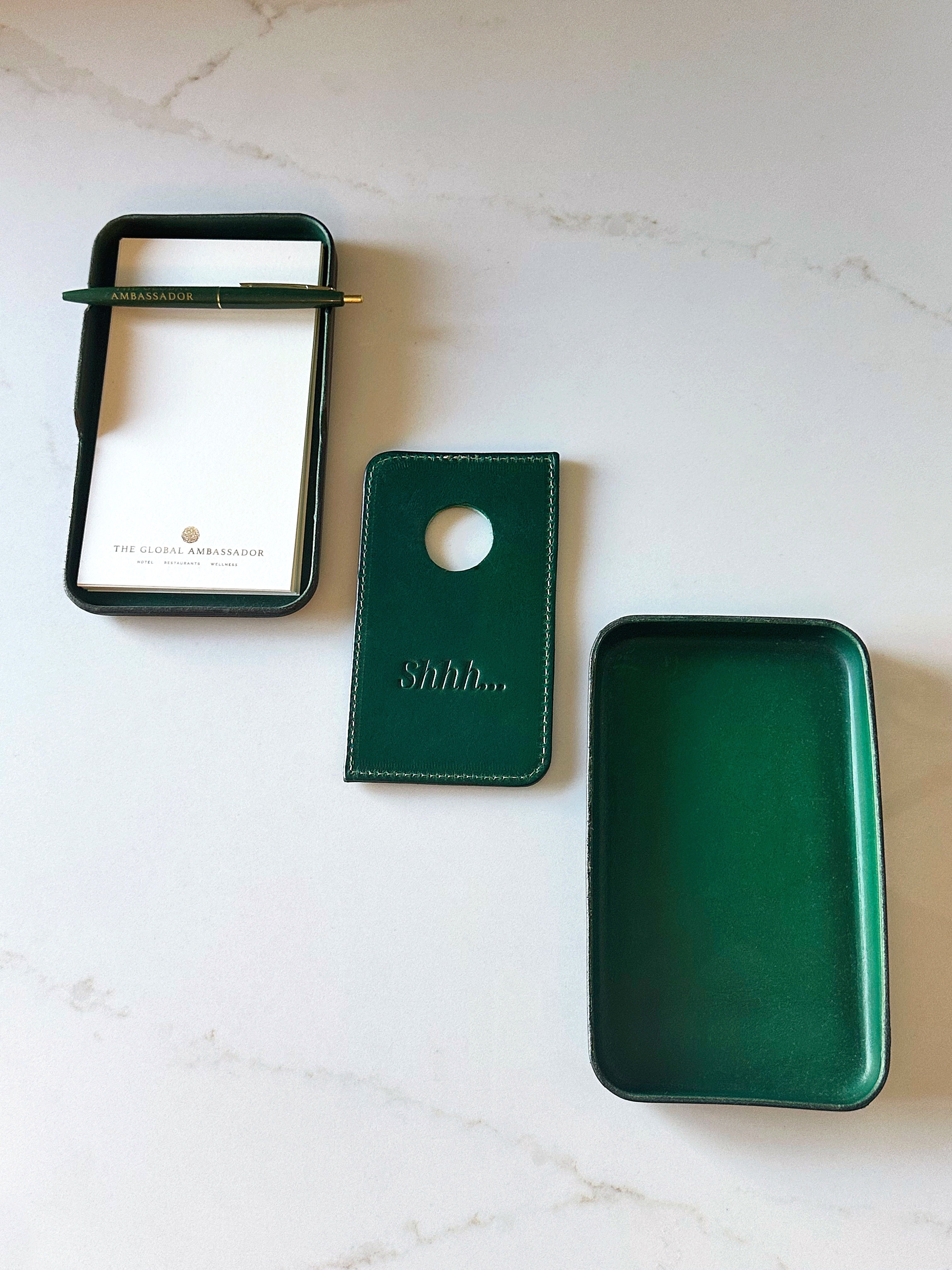 Three green leather items on a marble surface