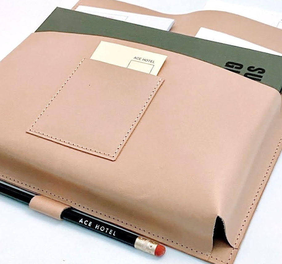 Beige planner cover with green interior pocket and ACE HOTEL pencil on a white background