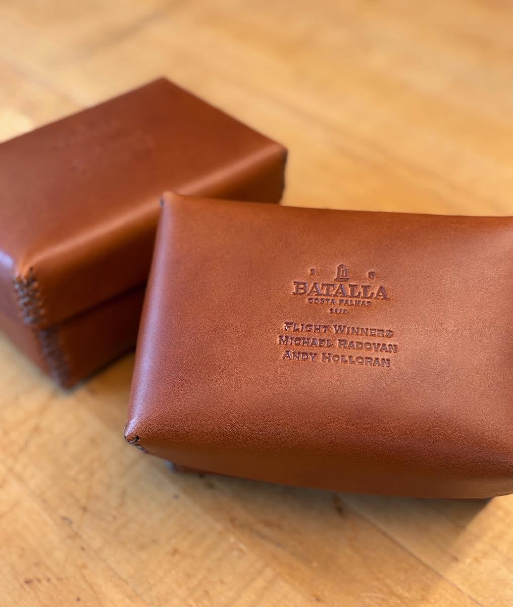 Two brown leather cases with branding on a wooden surface